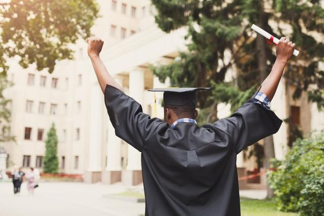 Man in cap and gown holding diploma.