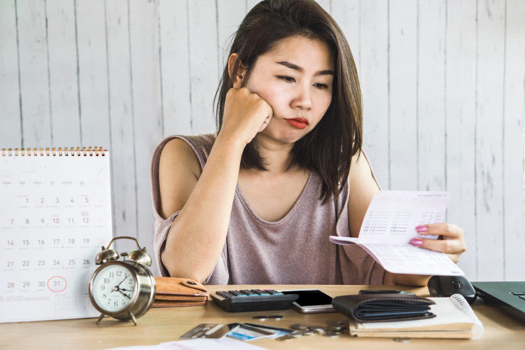 A student sits at a desk and looks at her checkbook.