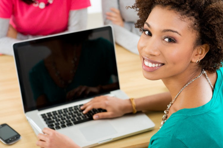 A woman sits at a desk in front of a laptop.