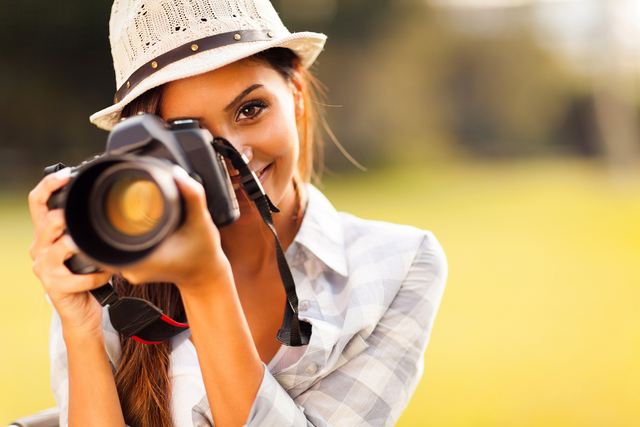 A woman points a camera lens toward the viewer.